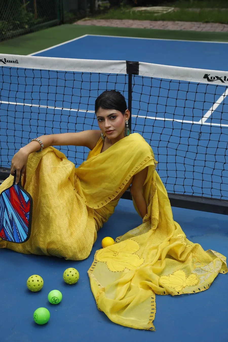 Model in a yellow saree on a pickleball court